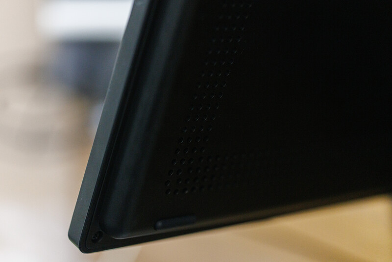 Close-up detail of a black device edge with textured surface against blurred background.