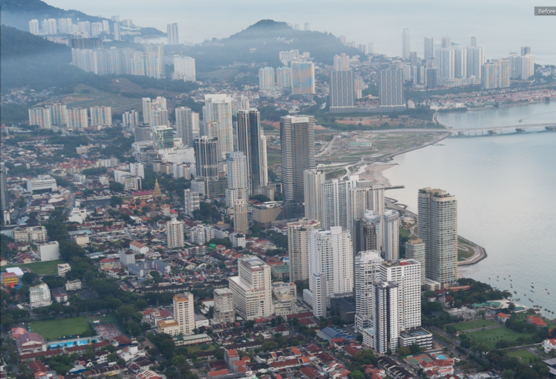 Aerial cityscape with high-rise residential towers overlooking a curved coastline and bay.