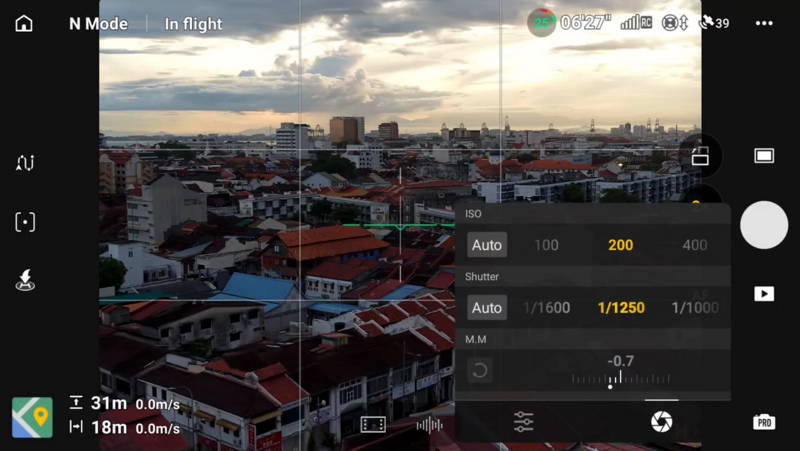 Screenshot of mobile camera app showing cityscape at golden hour with manual exposure controls displayed.