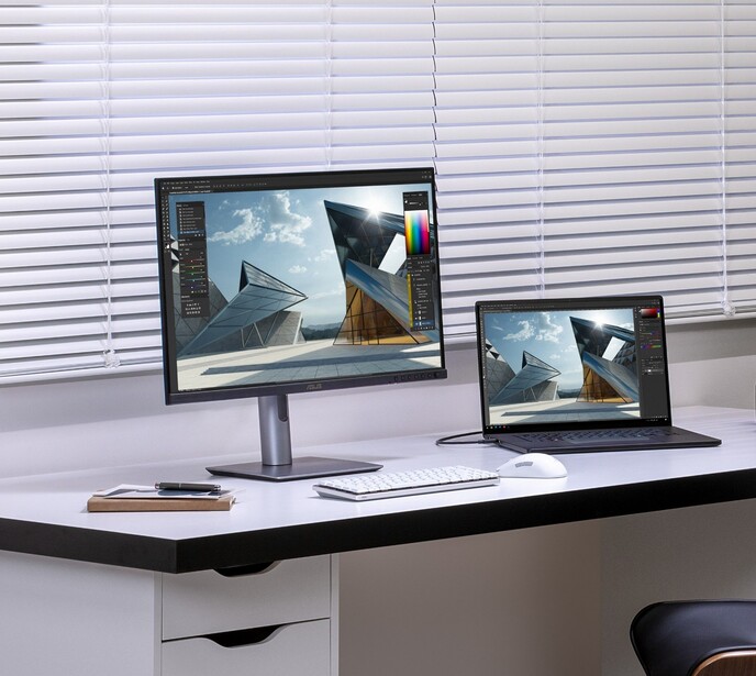Desktop setup with a monitor and laptop displaying the same architectural photograph in color grading software.