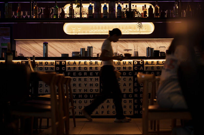 Person walking past illuminated storefront with wooden letter tiles spelling repeated text.