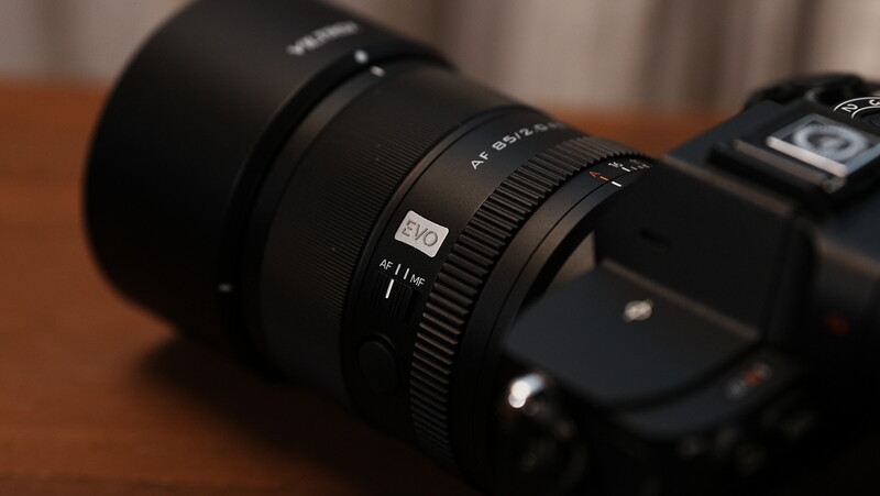 Camera lens with focus ring and depth of field markings mounted on black camera body.