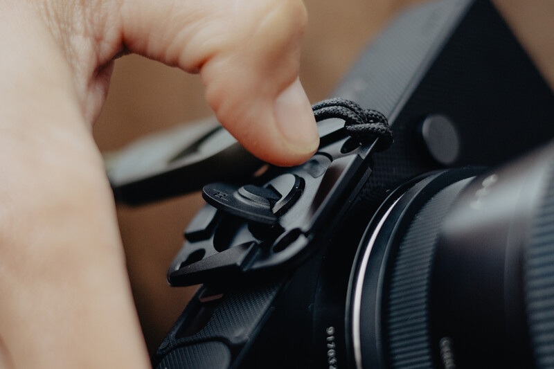 Child's hand adjusting a control dial on a black camera body with telephoto lens attached.
