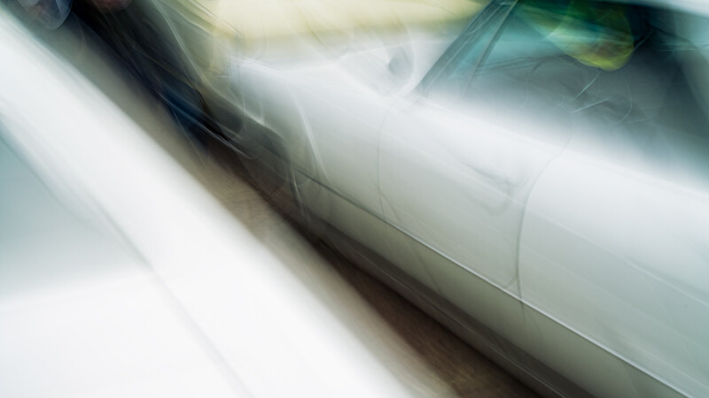 Silver sedan captured with motion blur during high-speed driving.