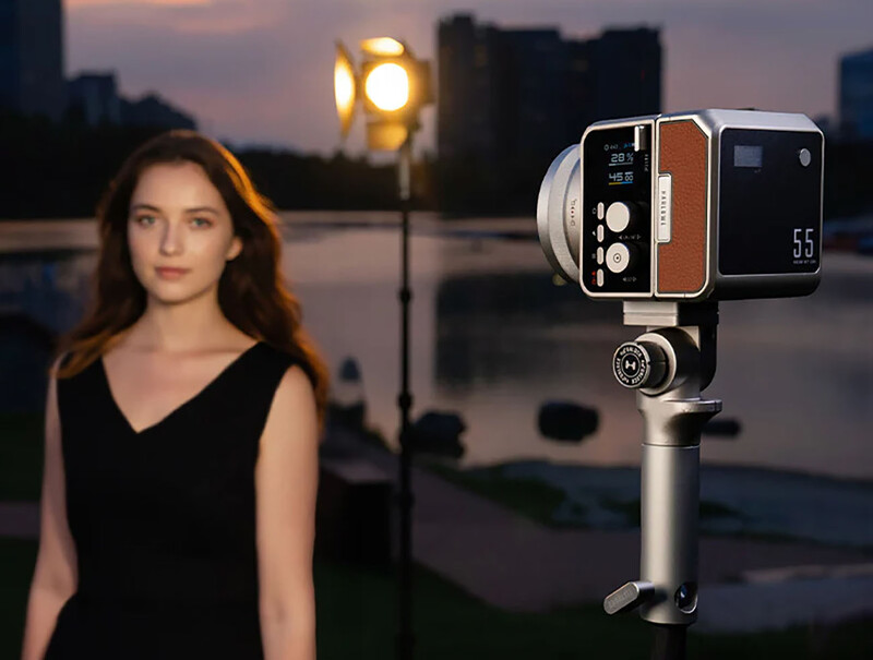 Vintage film camera mounted on tripod with woman in black top in soft-focus background during golden hour.