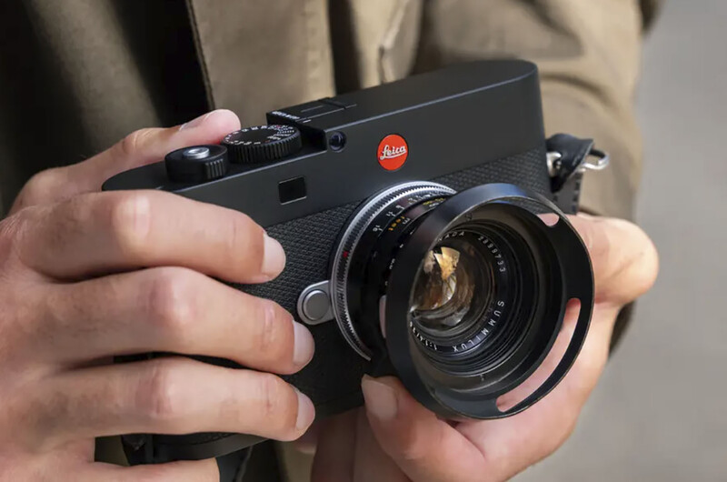 Leica M rangefinder camera with black body and standard lens held in photographer's hands.