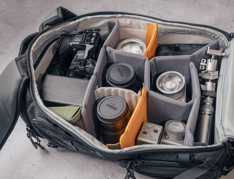 Organized camera bag interior with lenses, camera body, and accessories arranged in padded compartments.