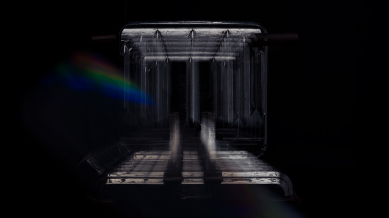 Interior view of a light tent or studio box with diffused lighting and rainbow light leak on black background.