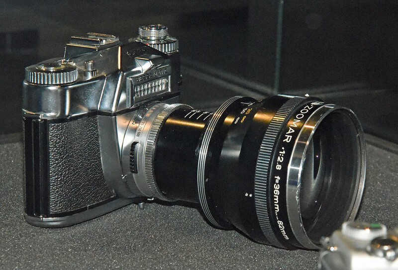 Vintage rangefinder camera with attached wide-angle lens on neutral gray surface.