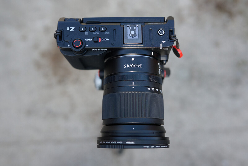 Top-down view of a mirrorless camera with attached telephoto lens on concrete surface.