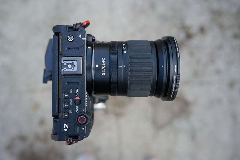 Top-down view of a compact digital cinema camera with attached zoom lens on concrete surface.