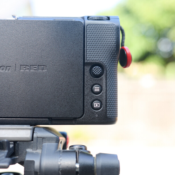 Compact external recorder mounted on top of a camera, showing control buttons and a red adjustment knob on its right side.