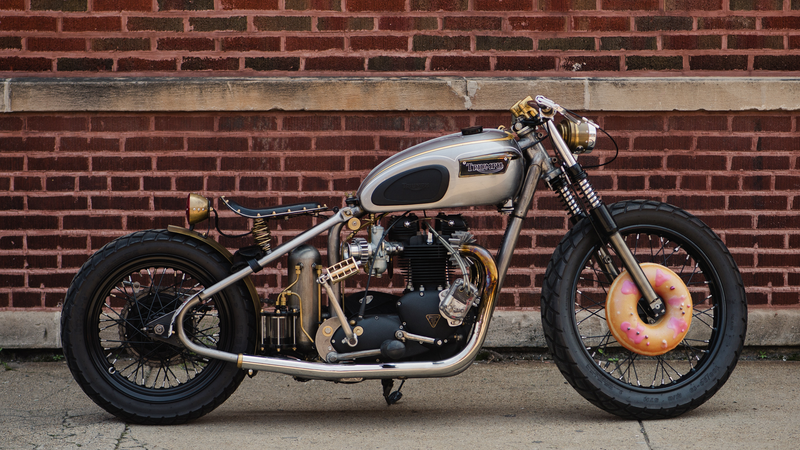 Custom motorcycle with teardrop fuel tank against red brick wall.