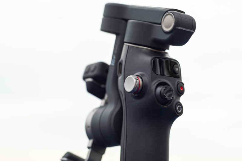 Close-up of a black camera gimbal head with control knobs and adjustment mechanisms mounted on a tripod.