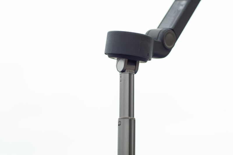 Close-up of a monopod head with ball-and-socket joint and adjustable arm attachment on a metal pole.