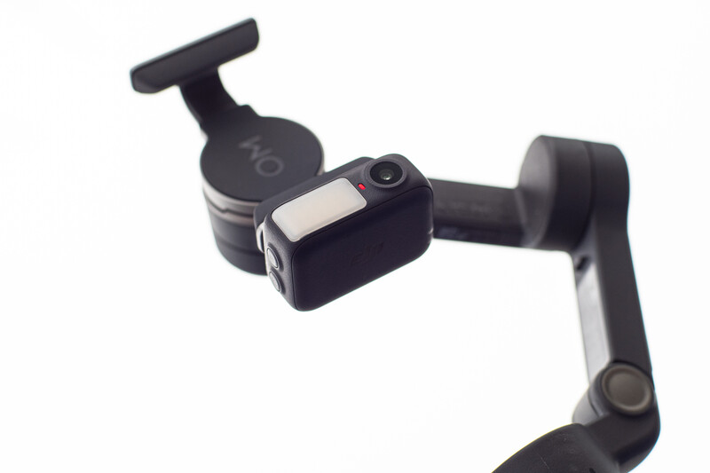 Three-axis gimbal stabilizer with articulated arms and hand grip mounted on dark frame.