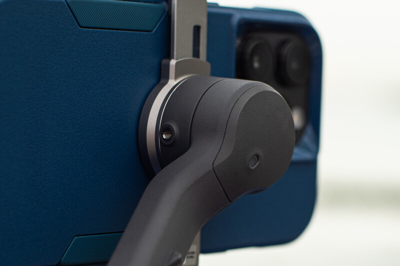 Close-up of a three-axis gimbal stabilizer mounted on a blue camera or smartphone device.