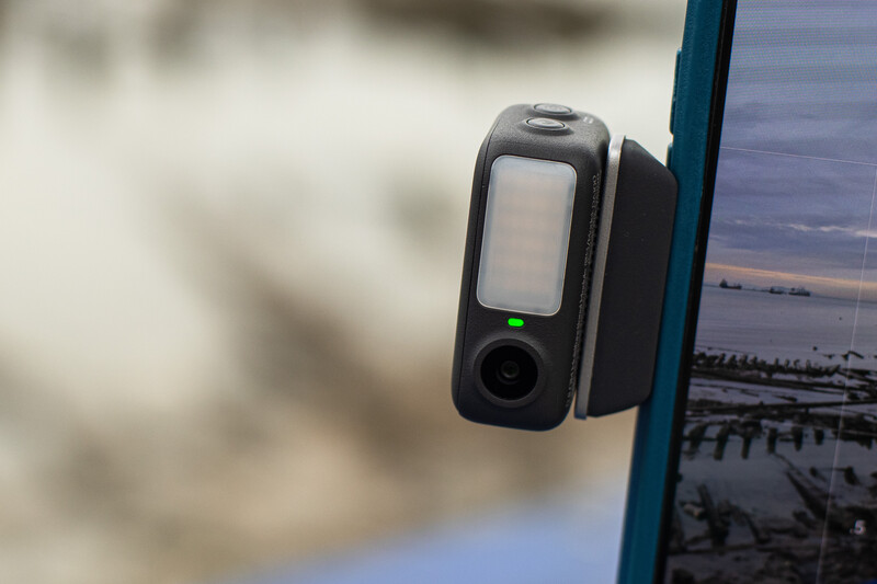 Dashcam mounted on vehicle windshield with landscape visible on screen.