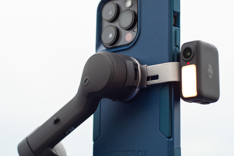 Gimbal stabilizer mounted on blue phone case with smartphone positioned for video capture.