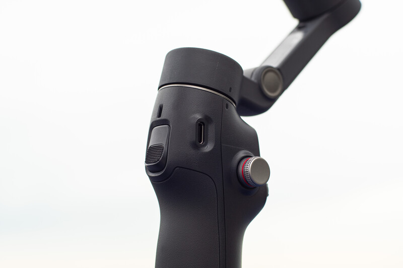 Close-up of a black gimbal stabilizer with articulated arm and control interface buttons.