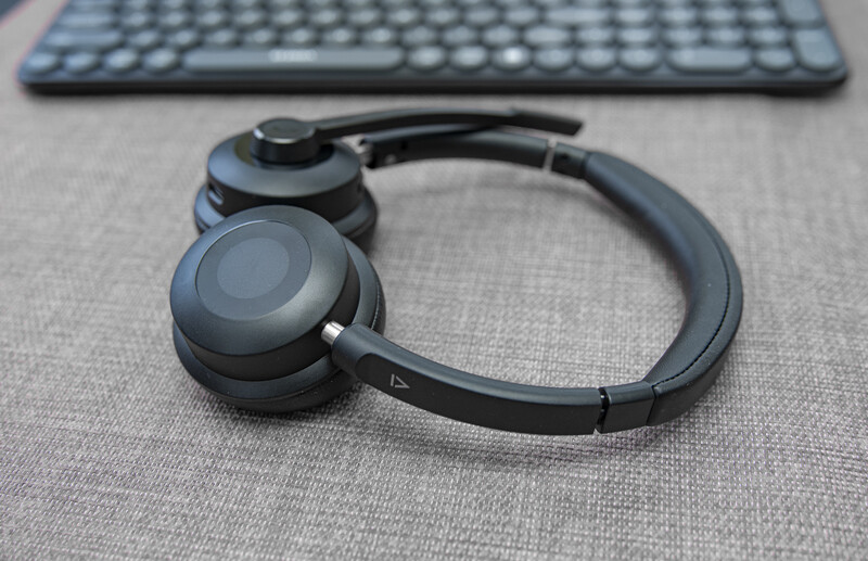 Black over-ear headphones with folded design resting on gray fabric surface next to keyboard.
