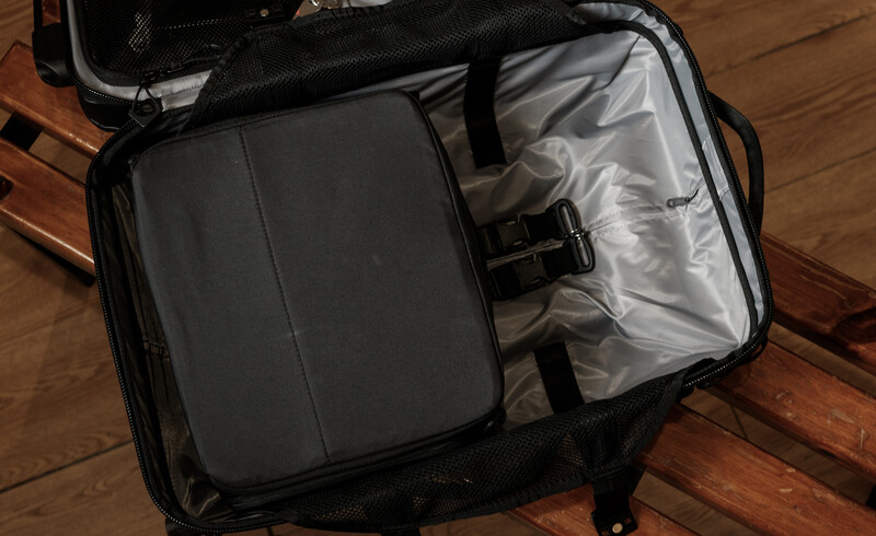 Open camera backpack with padded divider, gray fabric lining, and mesh storage pocket on wooden floor.