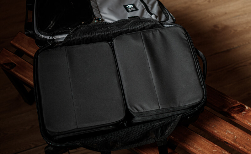Black camera backpack with multiple padded compartments open on a wooden surface.
