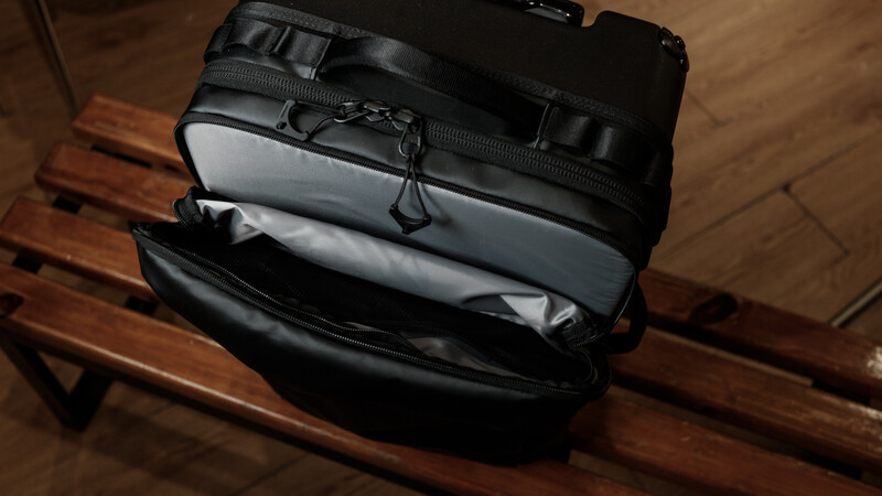 Black camera bag with gray padded interior compartment open on wooden surface.
