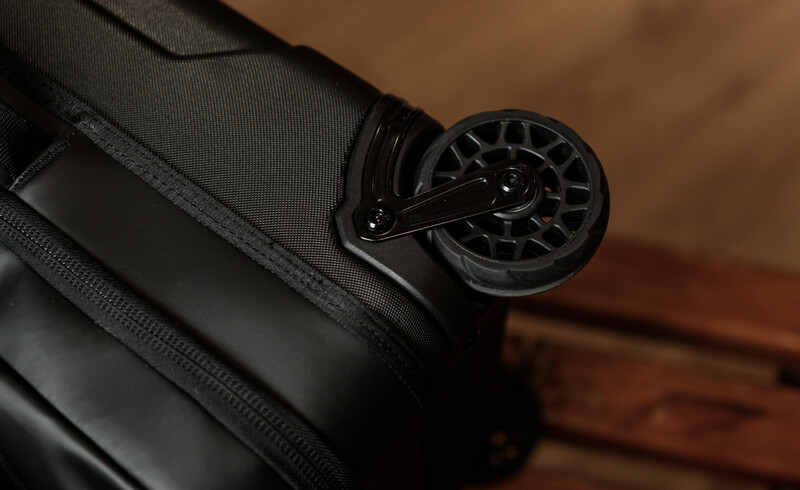 Close-up of a black fly fishing reel mounted on dark fabric gear against a wooden background.