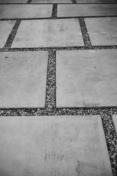 Geometric concrete pavement with dark gravel border strips creating a grid pattern.
