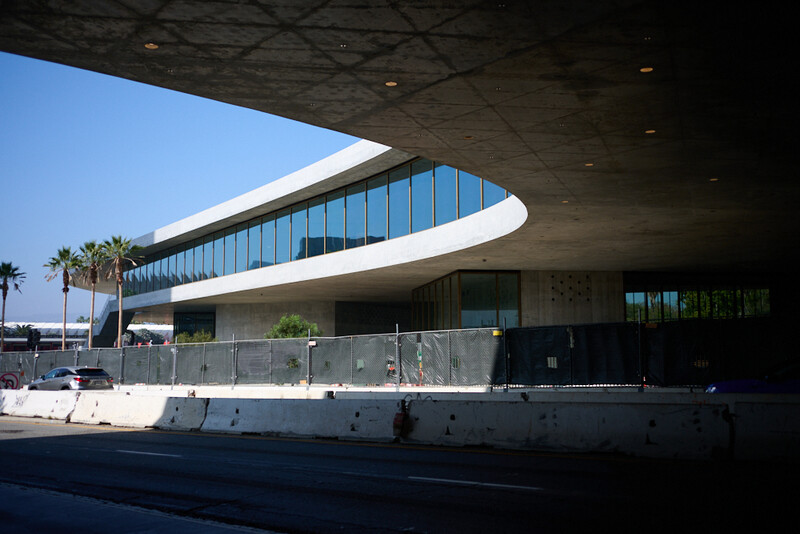 Modern curved waterfront building with glass windows and concrete structure under bright daylight.