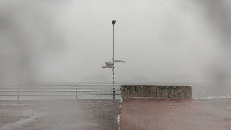 Tall metal antenna structure on a wet concrete platform shrouded in thick fog and mist.