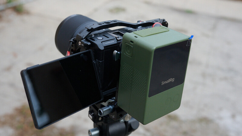 Cinema camera mounted on tripod with articulating monitor and follow focus system attached.