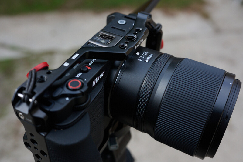 Nikon mirrorless camera with telephoto zoom lens mounted on a concrete surface.