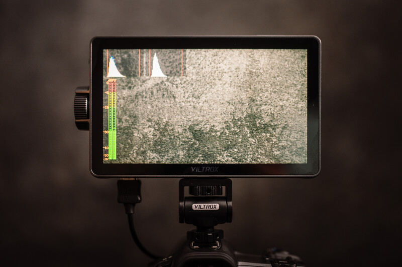 External monitor mounted on tripod displaying live video feed with histogram overlay.