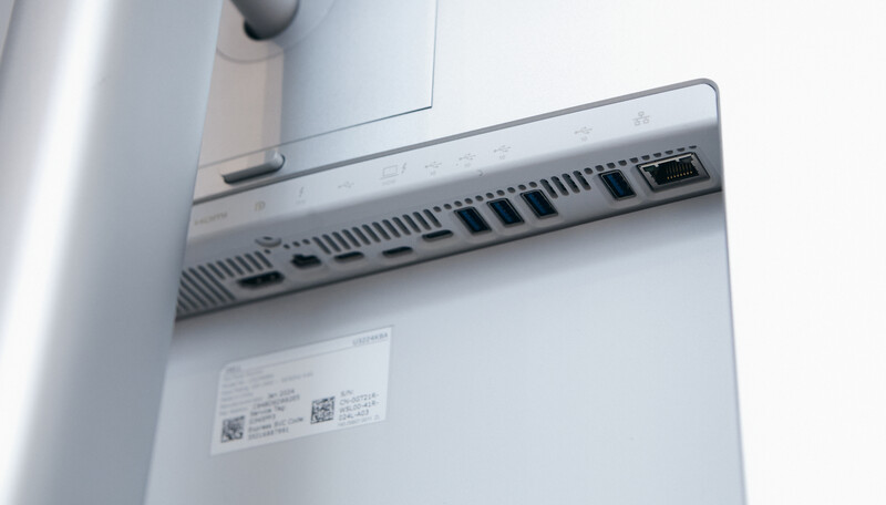 Close-up of a compact computer's rear ports and ventilation grille mounted on a white wall.