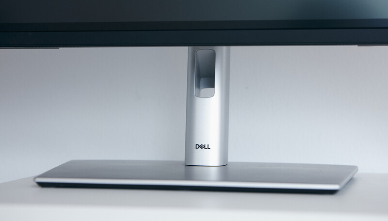 Dell monitor stand with white pedestal base and metallic silver foot on gray surface.