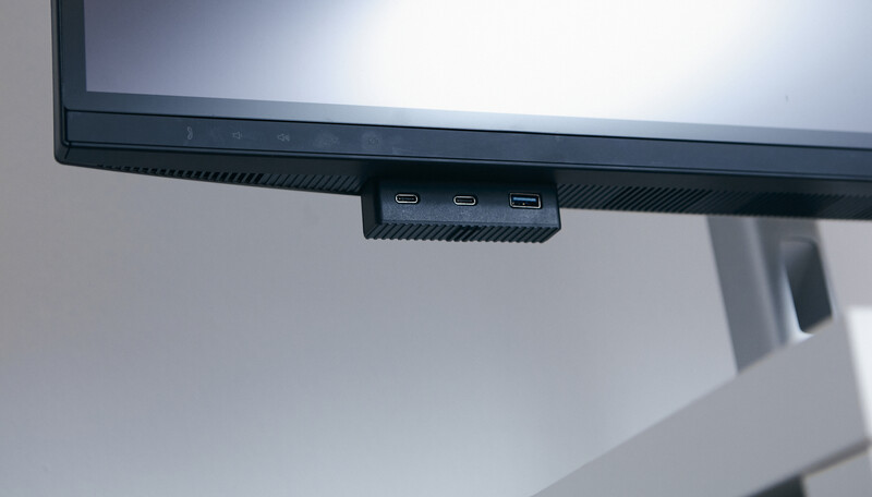 Monitor arm with three USB ports mounted beneath a display screen.