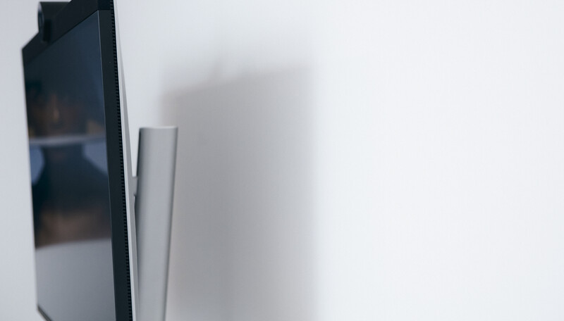 Close-up of a smartphone edge and silver stand against a white background with soft shadows.