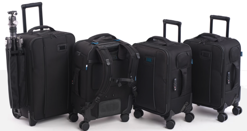 Four black travel cases and luggage pieces arranged in a row, including roller bags and a backpack.