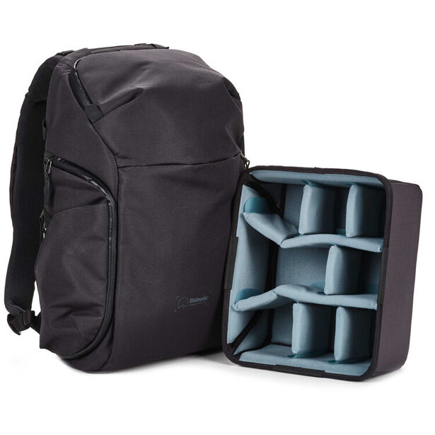 Black camera backpack with open divider insert showing padded compartments for lens and equipment storage.