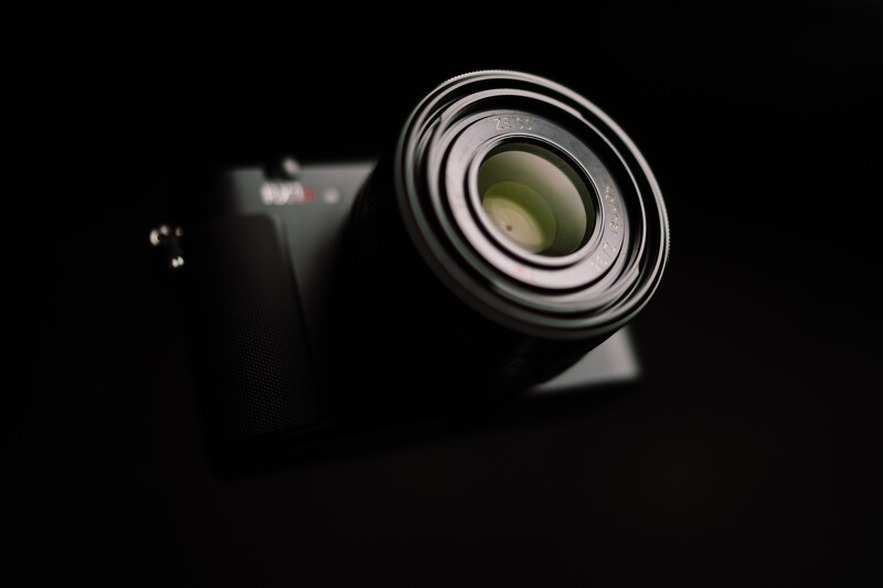Close-up of a telephoto lens mounted on a camera body against a dark background.