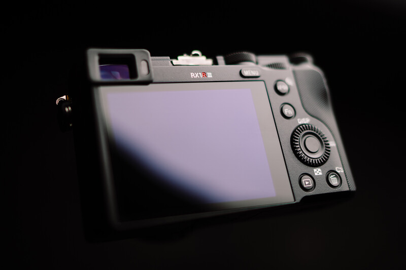 Compact digital camera with LCD screen displayed against black background.