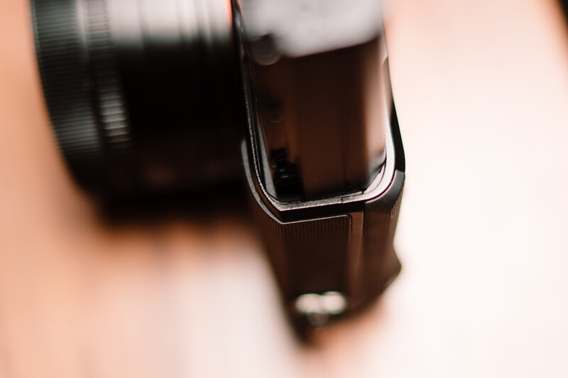 Close-up of a camera lens and flash unit with shallow depth of field and soft warm lighting.