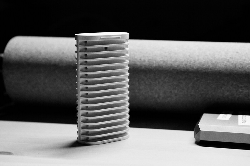 Close-up of a threaded metal bolt standing upright next to a cylindrical pipe against a black background.