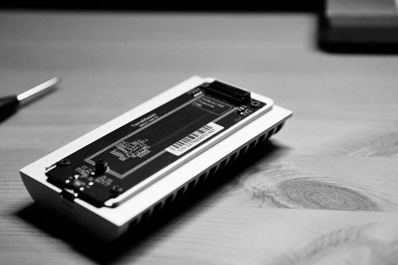 Black and white overhead shot of an open smartphone displaying its internal battery and components on a wooden surface.