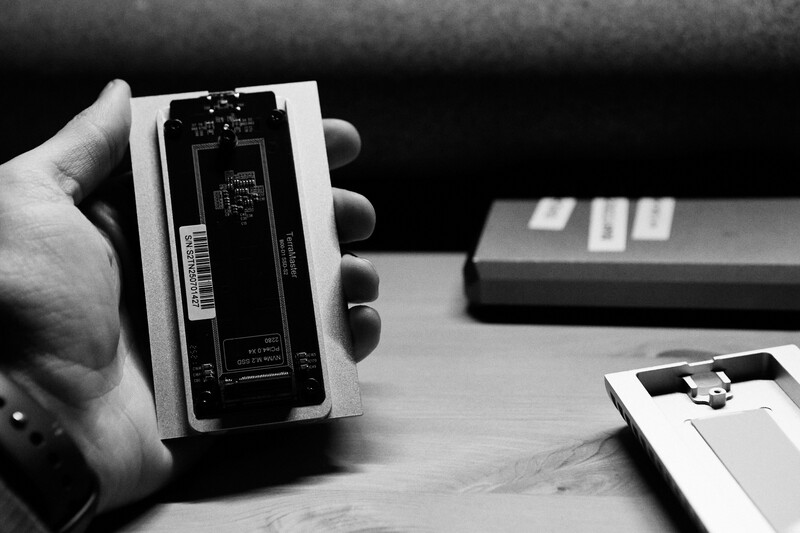 Hand holding smartphone with exposed internal components and circuit board visible against dark background.
