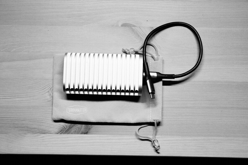 Coiled black cable attached to a white accordion-style cooling fin or heatsink on a wooden surface.
