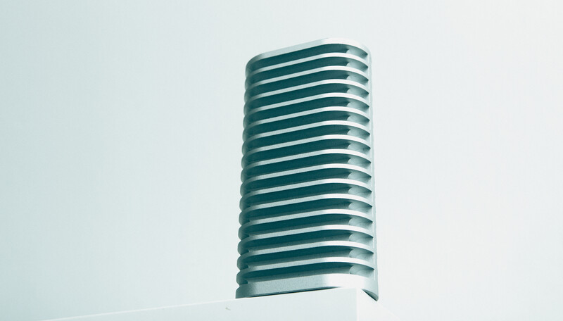 Cylindrical modern architecture with horizontal curved bands against clear sky.