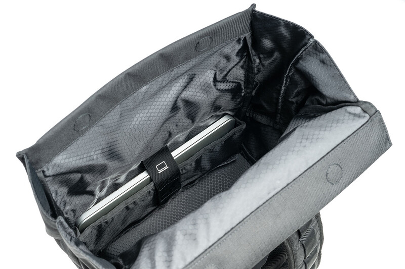 Gray camera backpack with open main compartment displaying padded dividers and a laptop sleeve with a camera lens inside.